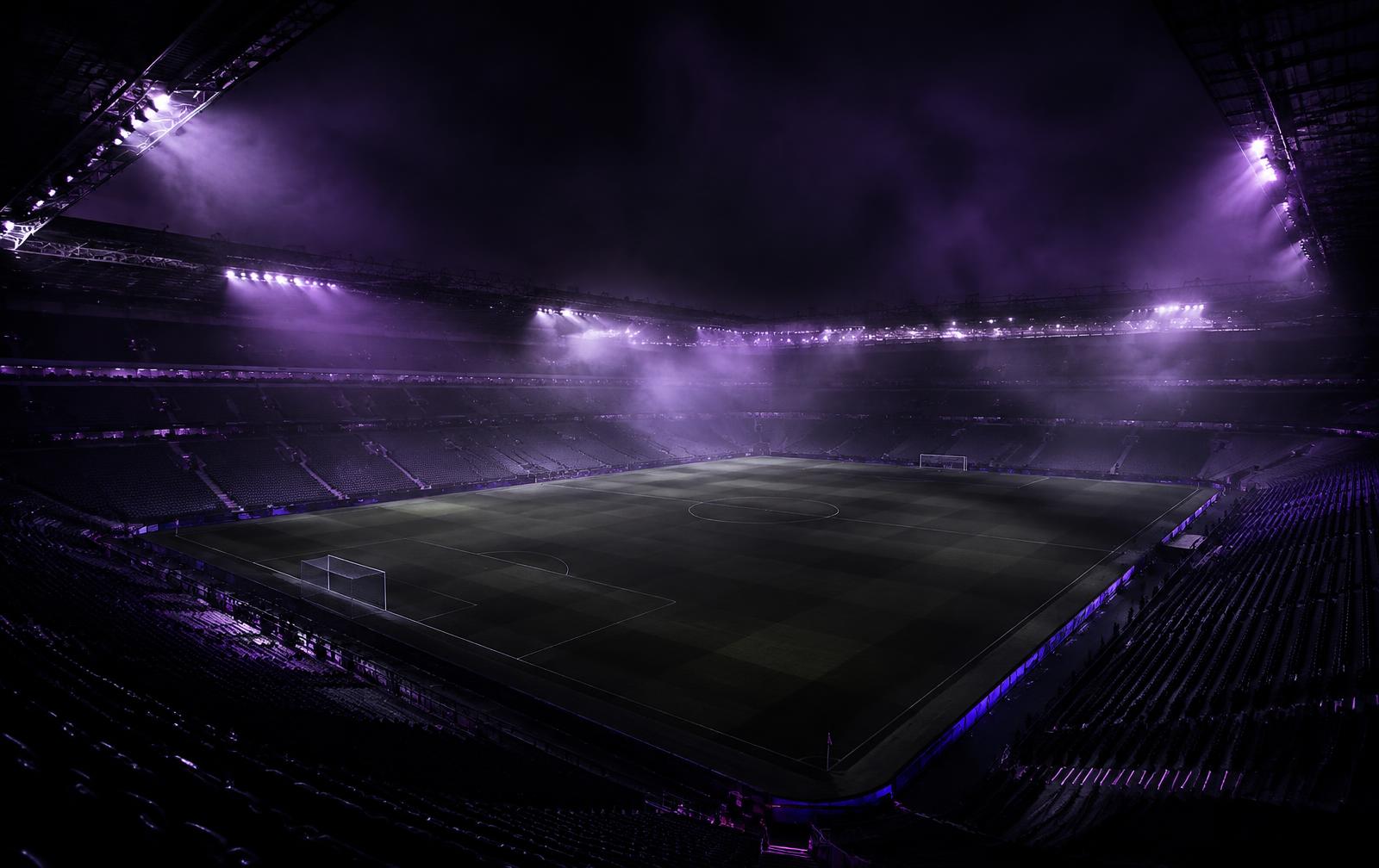 Stadion piłkarski nocą w fioletowym świetle reflektorów